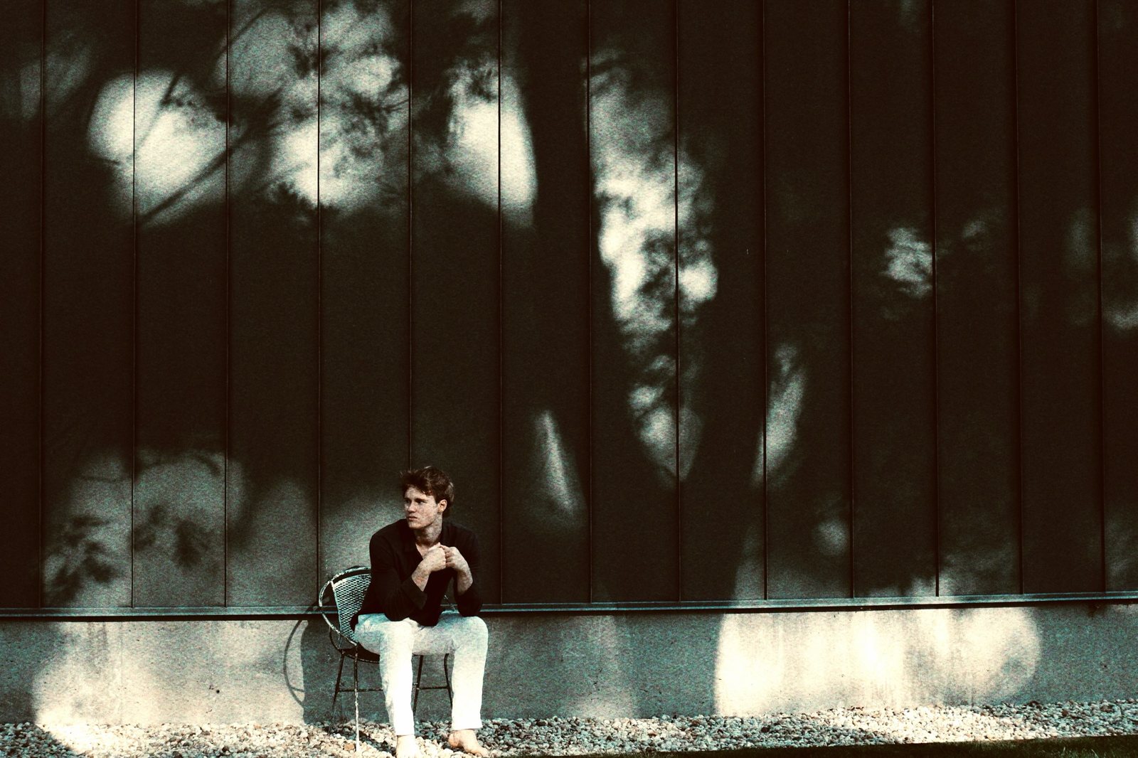 Max Bennett seated in his studio in front of a large dark painting